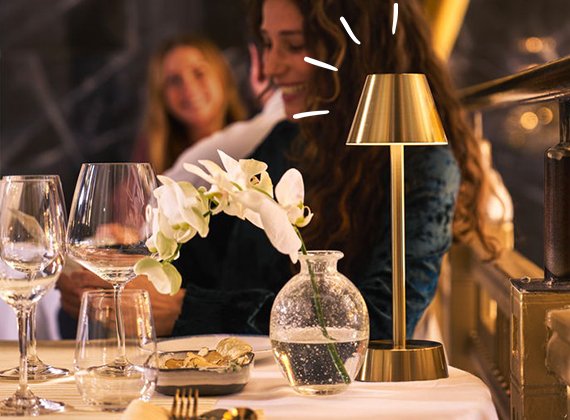 Friends enjoying a late dinner with a brass table lamp on the table